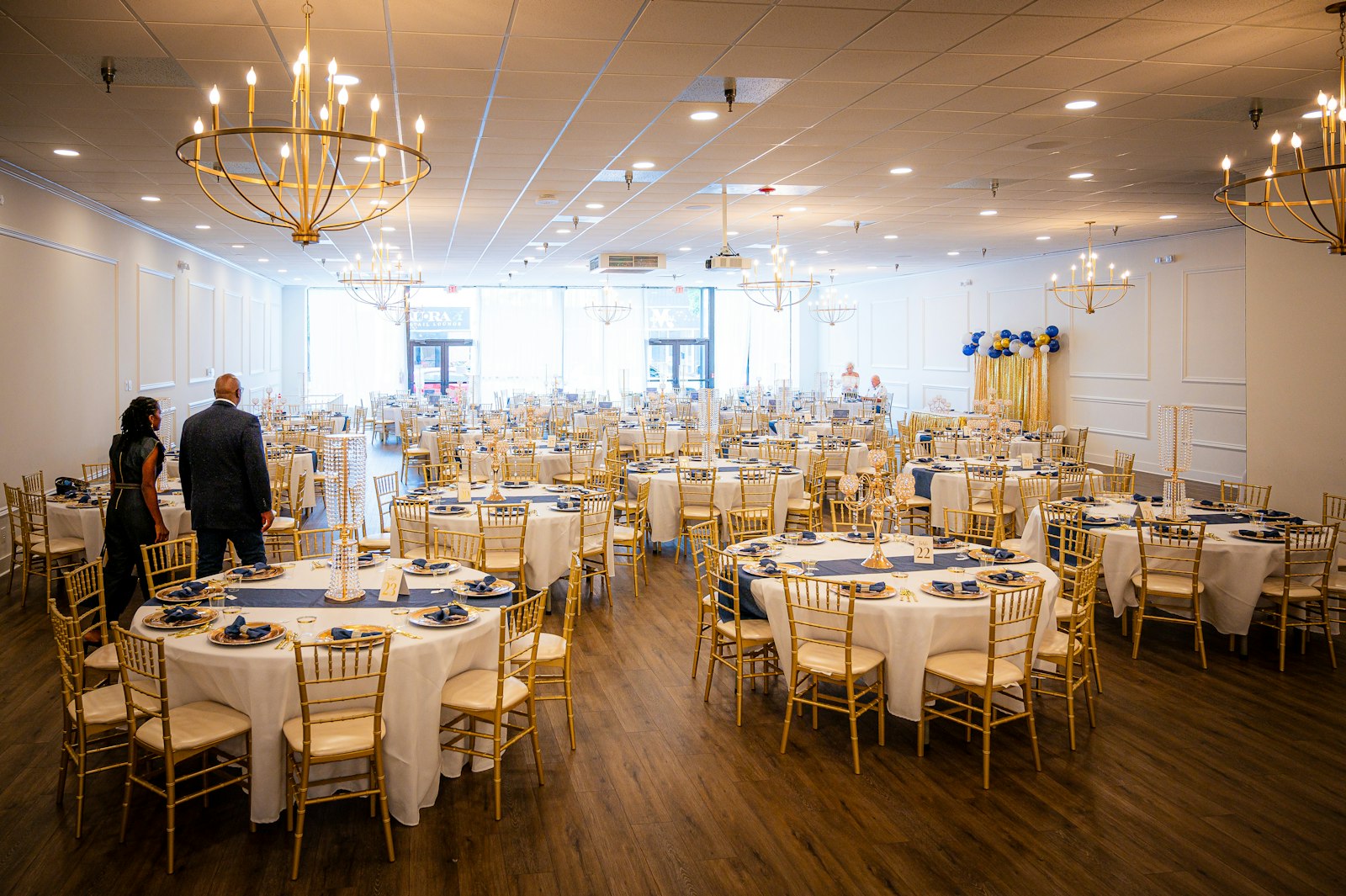 Elegant banquet hall set with round tables, white tablecloths and gold chairs before an event